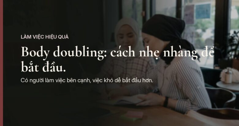 Trong một quán cà phê yên tĩnh, ánh sáng dịu, hai người ngồi sát nhau bên chiếc bàn gỗ, mỗi người viết vào cuốn sổ của riêng mình, phía trên là dòng chữ "Body doubling: cách nhẹ nhàng để bắt đầu."
